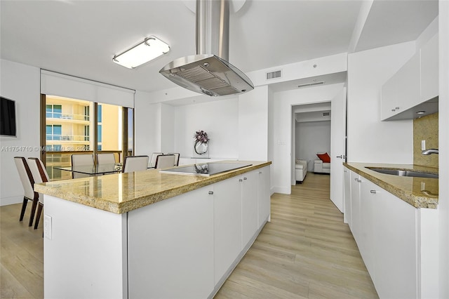 kitchen with visible vents, a sink, black electric cooktop, and white cabinets