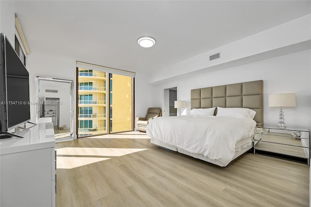 bedroom with floor to ceiling windows, visible vents, and light wood-style flooring