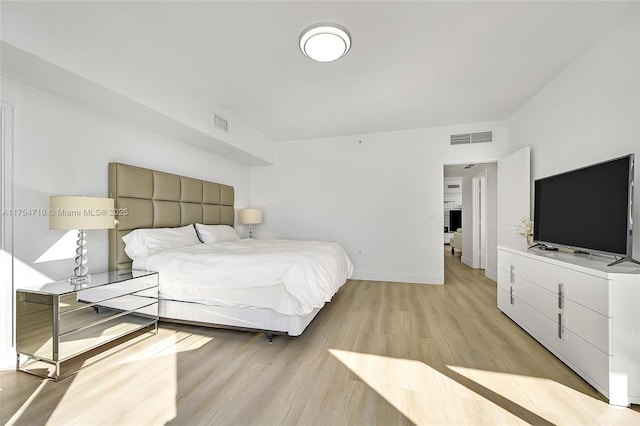 bedroom with visible vents, light wood-style flooring, and baseboards