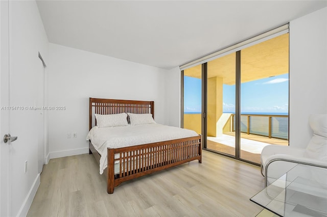 bedroom with light wood-style floors, access to outside, floor to ceiling windows, and baseboards