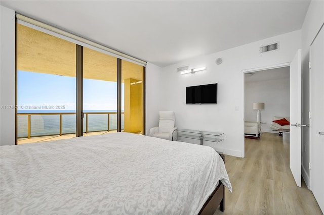 bedroom with visible vents, baseboards, access to outside, light wood-type flooring, and floor to ceiling windows