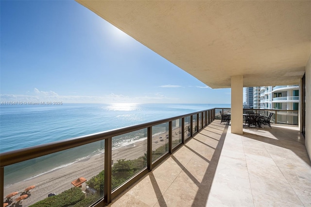 balcony featuring a water view and a beach view