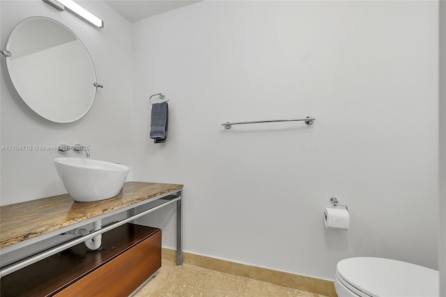 bathroom with toilet, vanity, and baseboards