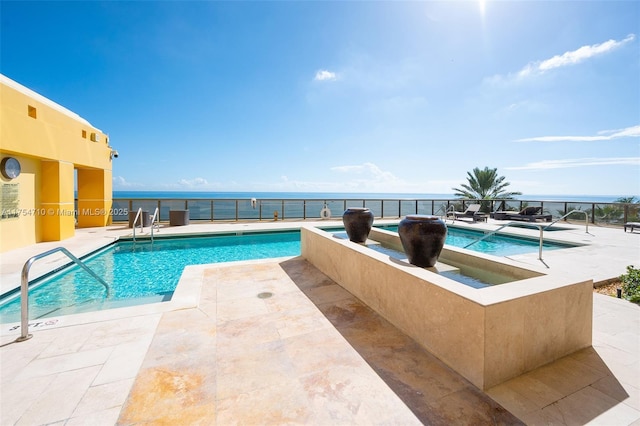 pool featuring a water view, a patio, and a jacuzzi