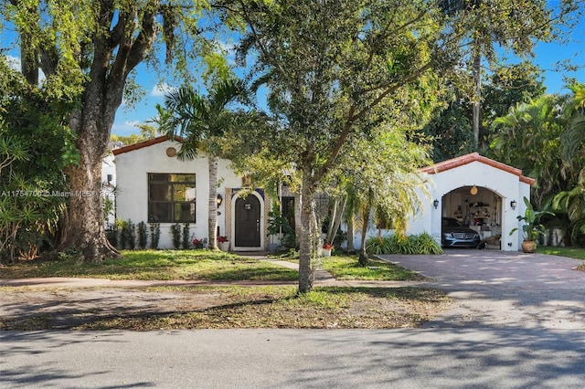 mediterranean / spanish-style home featuring a tiled roof, stucco siding, and driveway