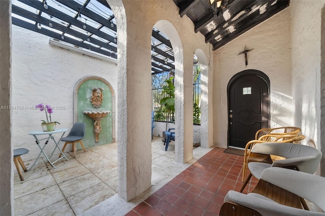 view of exterior entry featuring stucco siding and a patio area