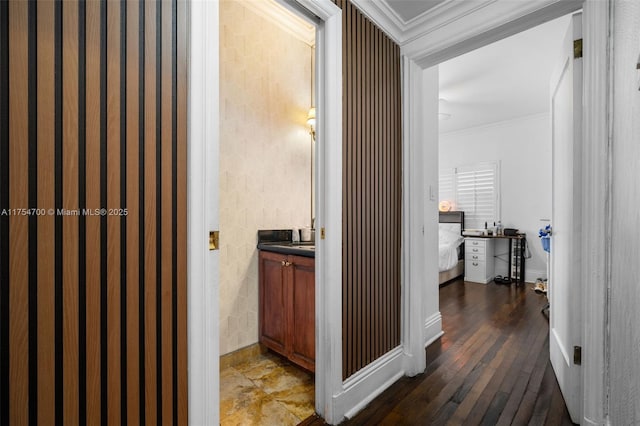 hall with wood-type flooring, crown molding, and baseboards