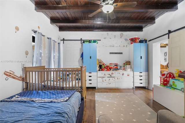 bedroom with a ceiling fan, wood finished floors, beam ceiling, wood ceiling, and a barn door