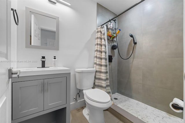 bathroom with toilet, tiled shower, and vanity