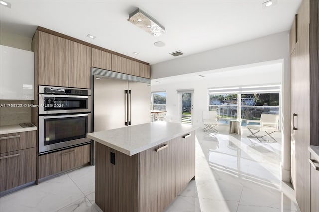 kitchen featuring appliances with stainless steel finishes, a center island, marble finish floor, and modern cabinets