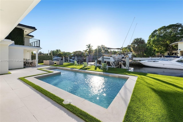 outdoor pool with a patio, a lawn, and a dock