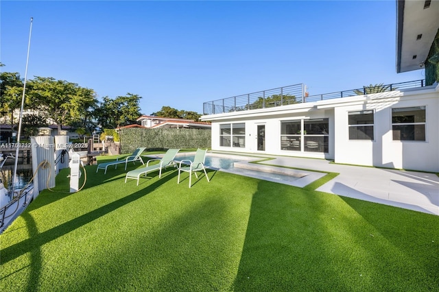 back of house with stucco siding, a patio area, fence, and a lawn