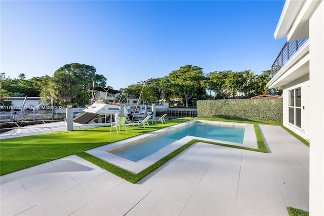 view of pool with a patio, fence, and a lawn