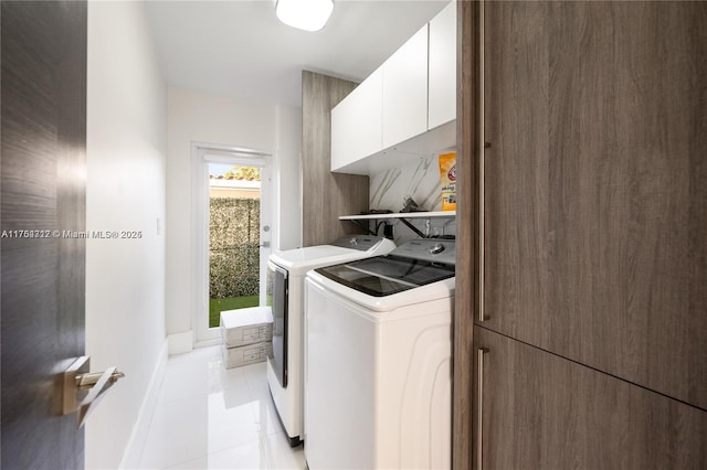 laundry room with baseboards, cabinet space, washing machine and clothes dryer, and light tile patterned floors