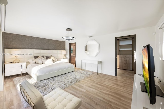 bedroom with light wood-style floors, visible vents, baseboards, and wallpapered walls