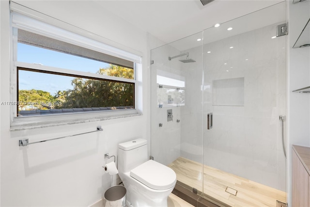 bathroom featuring a wealth of natural light, a shower stall, and toilet