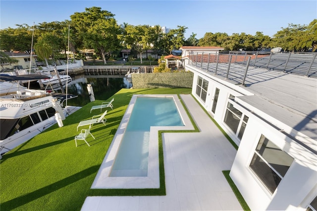 view of pool with a water view, a yard, and a boat dock