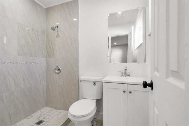 full bath featuring a tile shower, vanity, and toilet