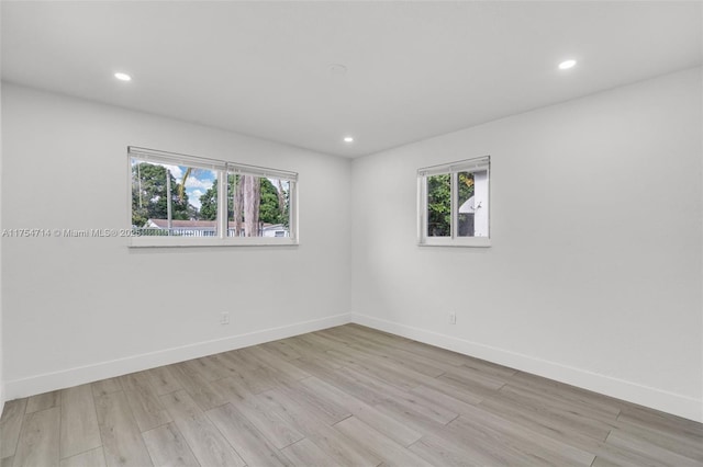 spare room with baseboards, wood finished floors, and recessed lighting