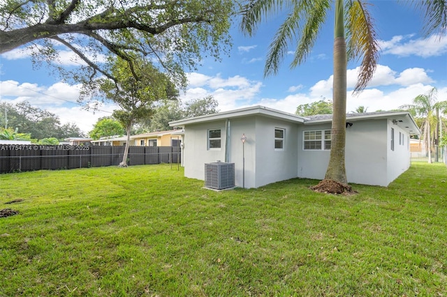 back of house featuring fence private yard, stucco siding, cooling unit, and a yard