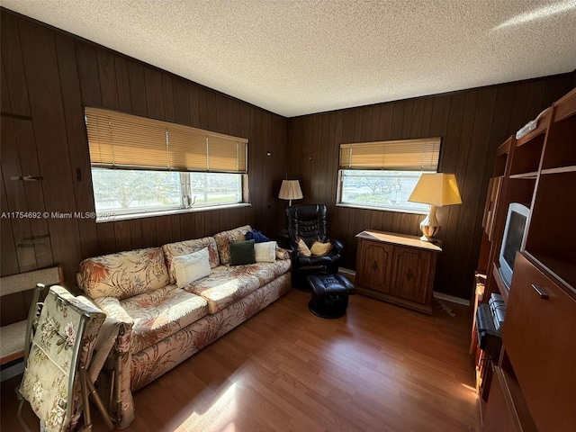 living area with a textured ceiling, wood walls, and wood finished floors