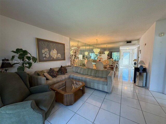 living room with a chandelier, visible vents, a textured ceiling, and light tile patterned floors