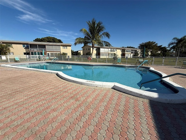 community pool with a patio area and fence