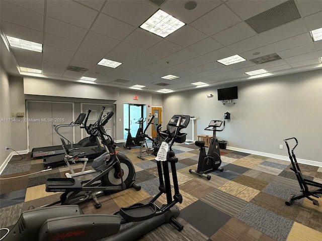 exercise room with a drop ceiling, visible vents, and baseboards