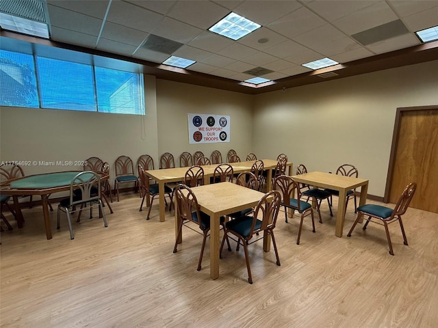 dining area with a drop ceiling, light wood-type flooring, and visible vents