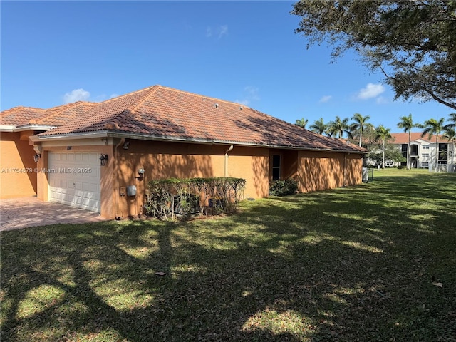 exterior space with a garage, a tile roof, a yard, and stucco siding