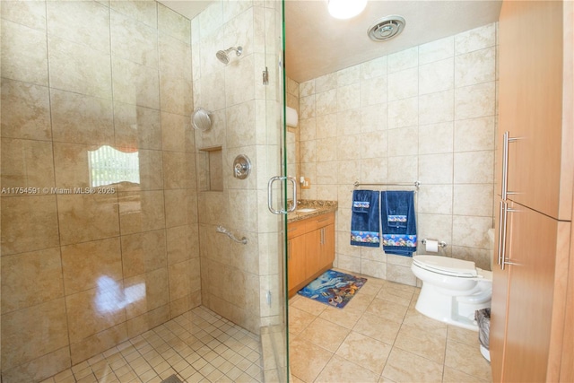 bathroom with toilet, tile patterned flooring, vanity, a shower stall, and tile walls