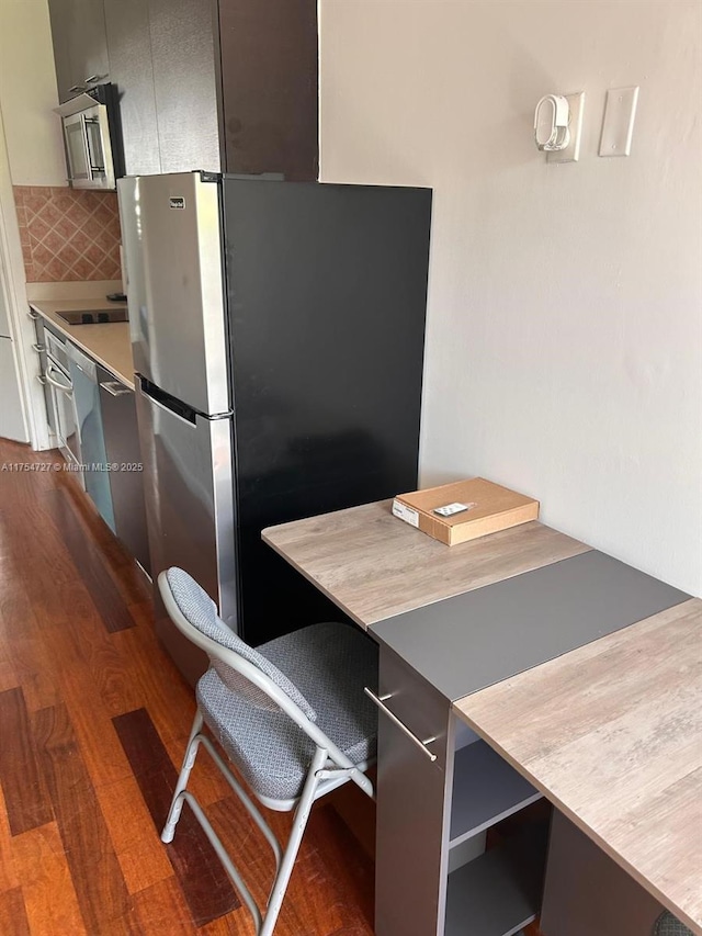 kitchen featuring black electric stovetop, a breakfast bar, backsplash, freestanding refrigerator, and dark wood finished floors