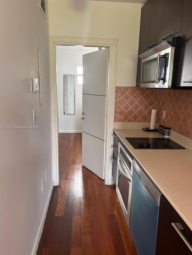 kitchen featuring dark wood-style flooring, tasteful backsplash, light countertops, visible vents, and appliances with stainless steel finishes