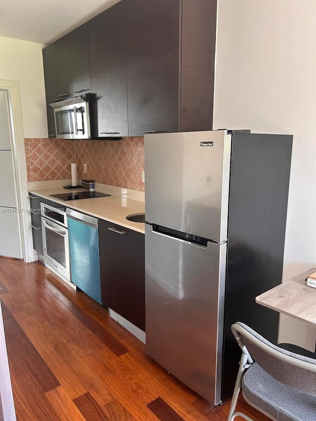 kitchen featuring appliances with stainless steel finishes, light countertops, dark wood finished floors, and decorative backsplash