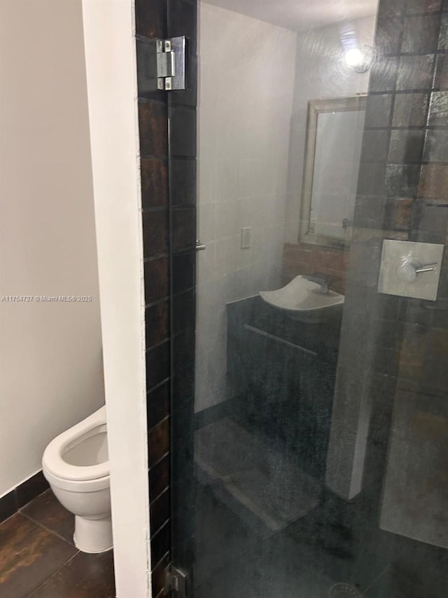 full bathroom with tile patterned flooring, tiled shower, a sink, and toilet