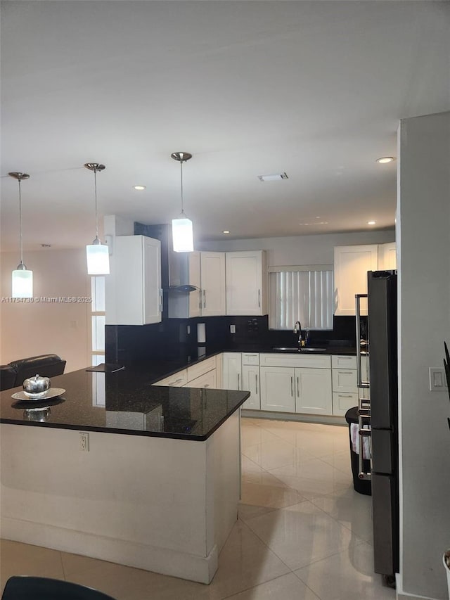 kitchen featuring a sink, white cabinets, freestanding refrigerator, tasteful backsplash, and pendant lighting