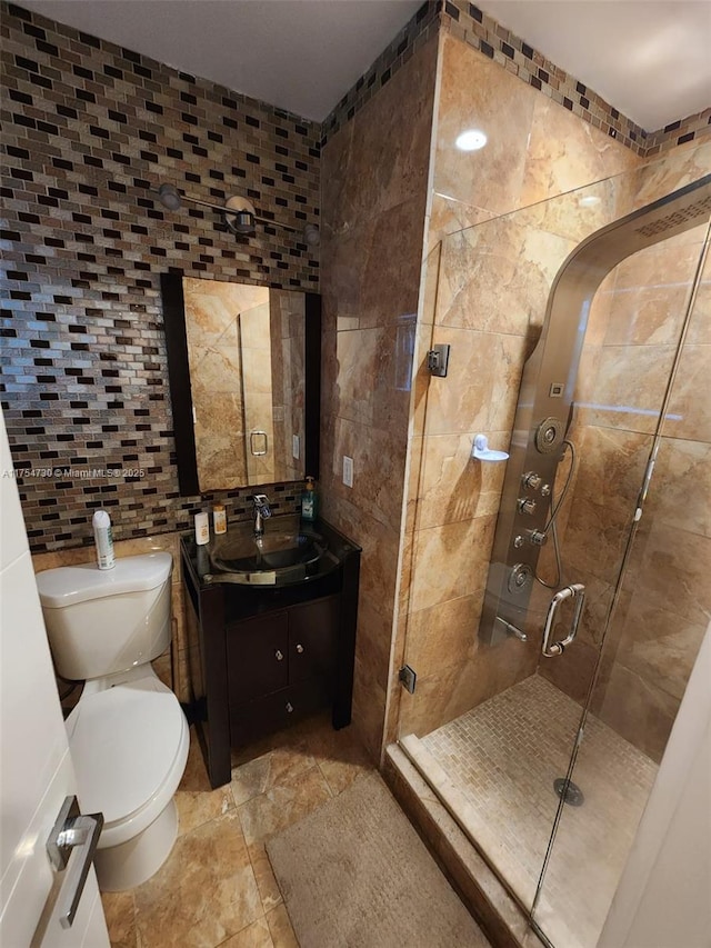 bathroom with toilet, a stall shower, vanity, and tile walls