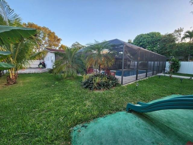 exterior space featuring a fenced in pool, glass enclosure, a lawn, and a fenced backyard