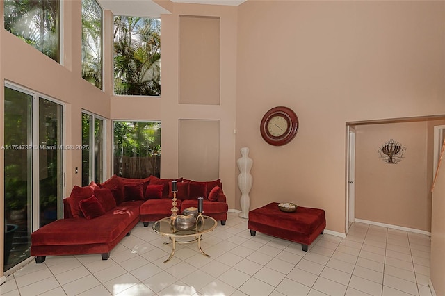 living room featuring baseboards, a towering ceiling, and light tile patterned floors