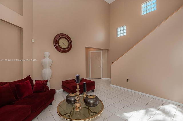 living room featuring baseboards, light tile patterned floors, stairway, and a towering ceiling