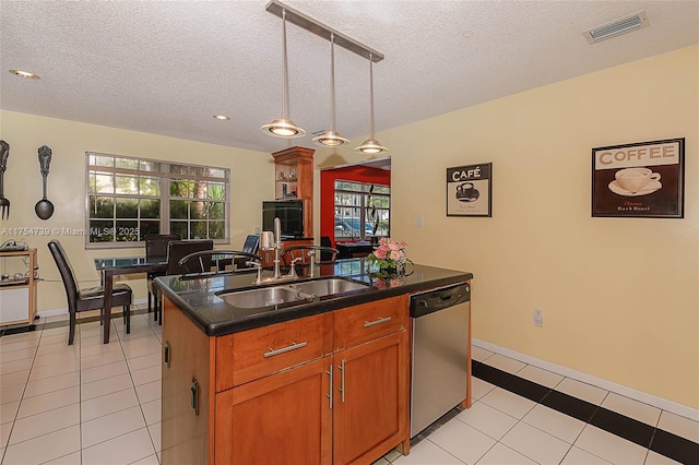 kitchen with a textured ceiling, visible vents, dark countertops, stainless steel dishwasher, and a sink