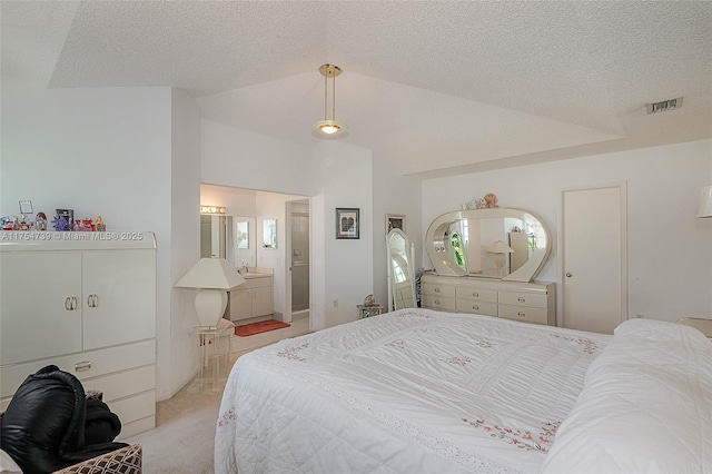 bedroom with visible vents, light colored carpet, a textured ceiling, a sink, and vaulted ceiling