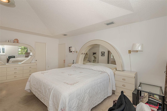 bedroom featuring visible vents, a textured ceiling, and light colored carpet