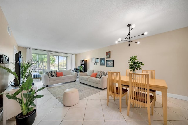 living area with light tile patterned floors, baseboards, a textured ceiling, and a chandelier