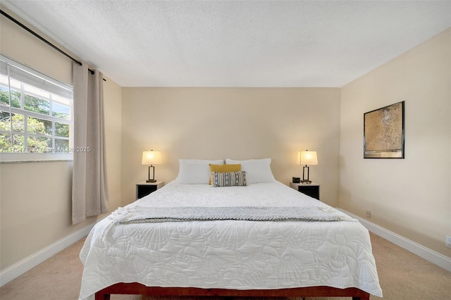 bedroom with baseboards, a textured ceiling, and light colored carpet