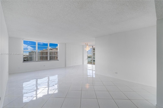 empty room featuring light tile patterned floors, baseboards, and a textured ceiling