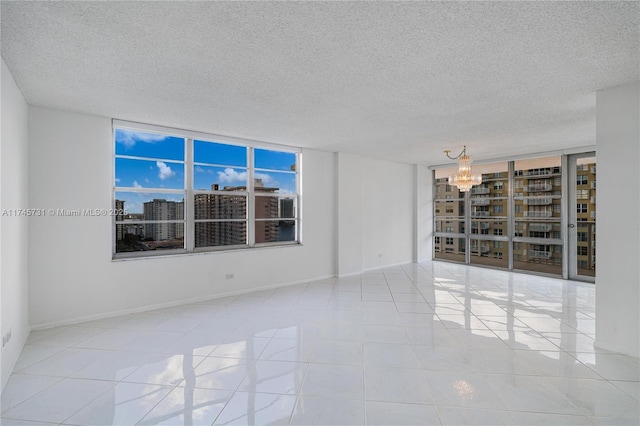 spare room featuring an inviting chandelier, a textured ceiling, a city view, and tile patterned floors