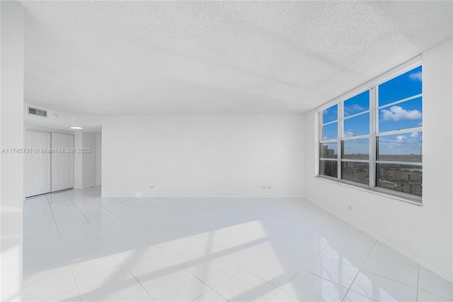 tiled spare room featuring visible vents and a textured ceiling