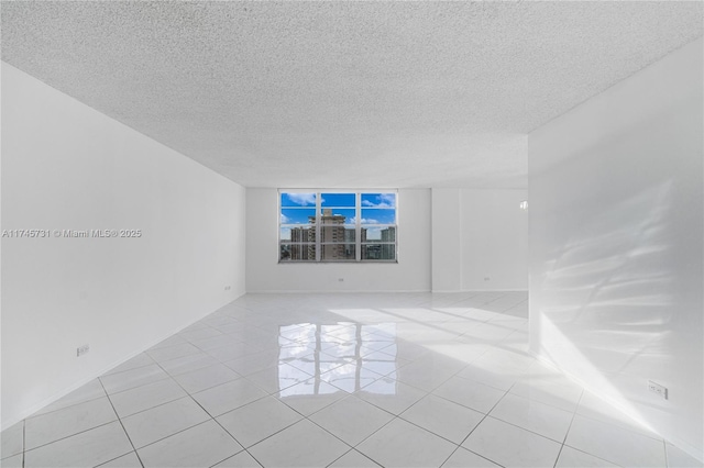 spare room featuring light tile patterned floors and a textured ceiling