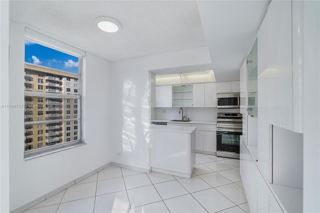 kitchen featuring appliances with stainless steel finishes, white cabinets, a sink, and light tile patterned flooring